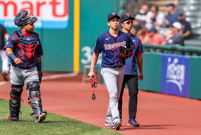 Twins righthander Kenta Maeda (center) walks catcher Willians Astudillo (left) and his interpreter Daichi Sekizaki.